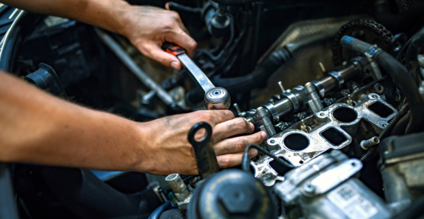 Close up view of a mechanic fixing the engine of a vehicle.