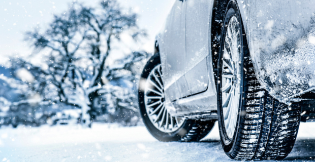 A car driving down a snowy road on a winter day with winter tires. 