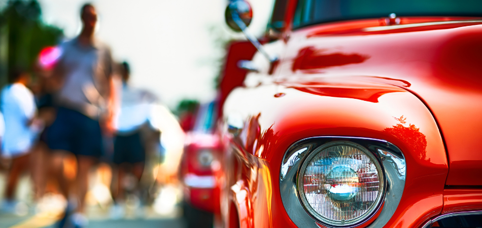 Classic cars on display at a classic car show in Canada with people walking by to view the cars during the summer.