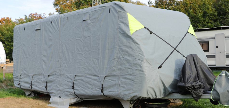 A winterized RV is protected with a gray weatherproof cover showing an example of winterizing your RV.