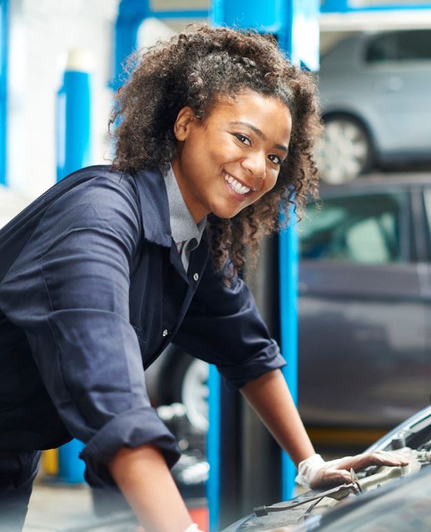 A mechanic leans over the car she's working on.