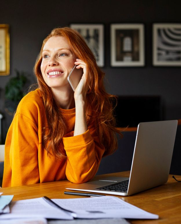 A woman on the phone with her laptop open in front of her.