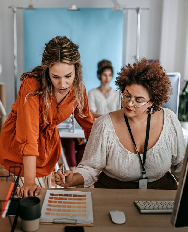 Two women review designs in an open concept office.