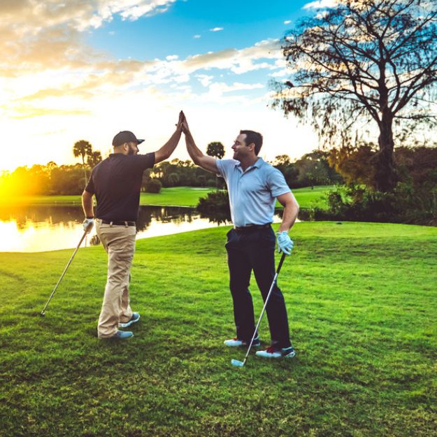 Two friends high-five on the green.