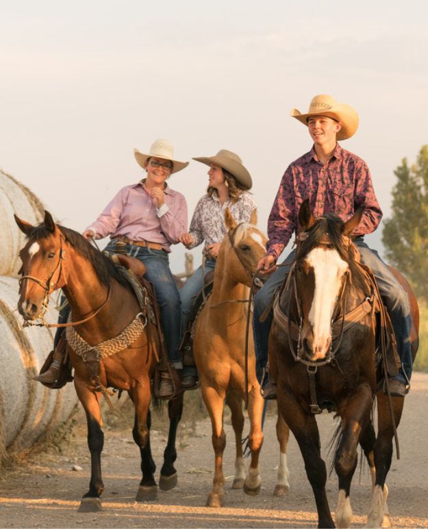 Three riders on horseback arrive back at the ranch from a fun trail ride