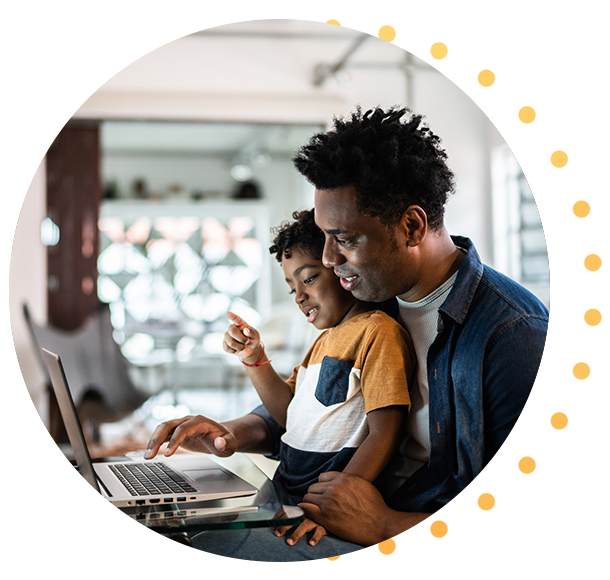 Man using laptop with son sitting on lap at home