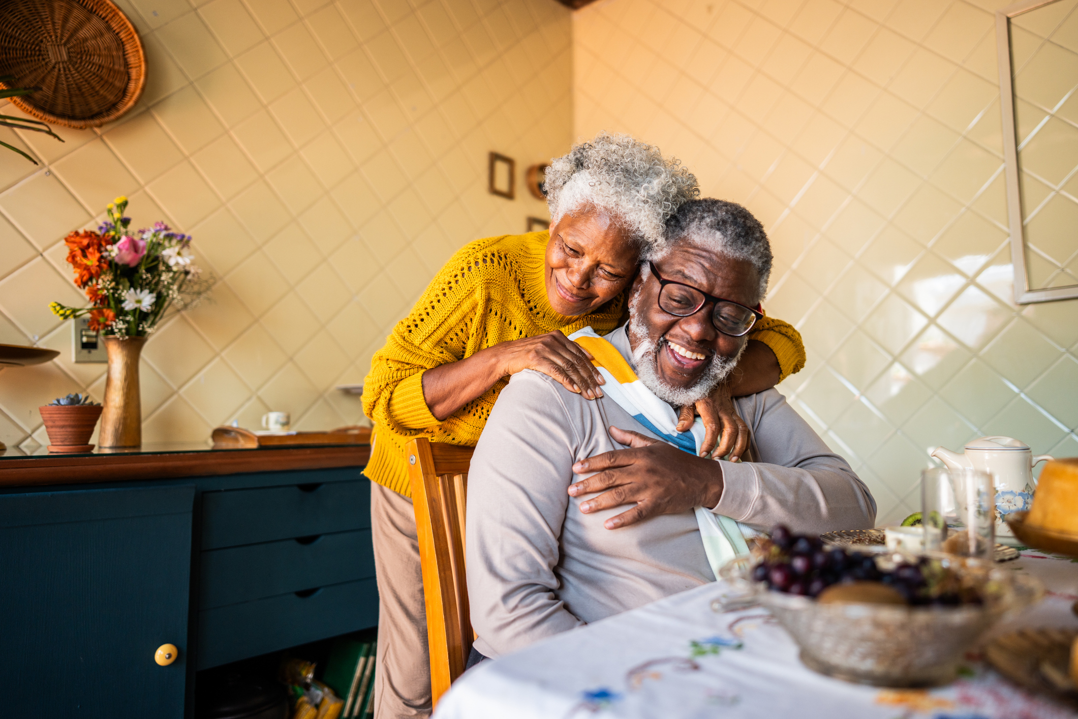 Mature couple embracing at kitchen table at home