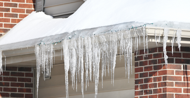 Row of icicles on the roof of a brick house.