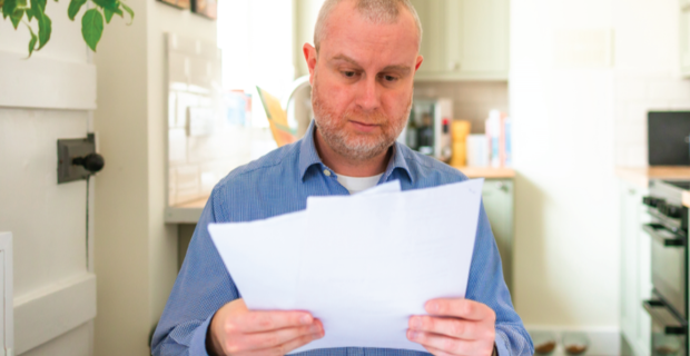 Person in a blue shirt reading papers in a kitchen.