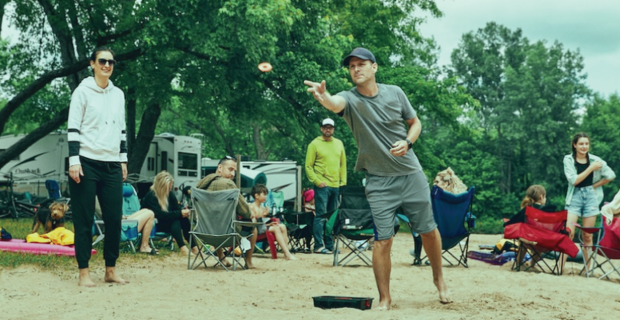 Man playing the game of washers at a campground.