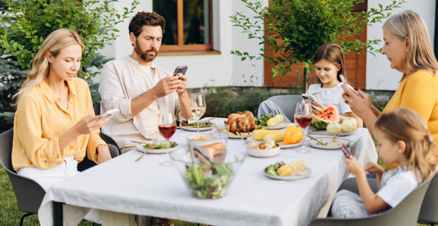 A family gathered around the table for a meal, with each member absorbed in their screen.